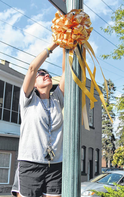 125576871_web1_Eric-Spiecher-3
Jennifer Bonita, Eric Speichers aunt, uses a step stool to place a gold ribbon on a light standard on Luzerne Ave., West PIttston, during the ribbon campaign in 2019.
Tony Callaio | File photo