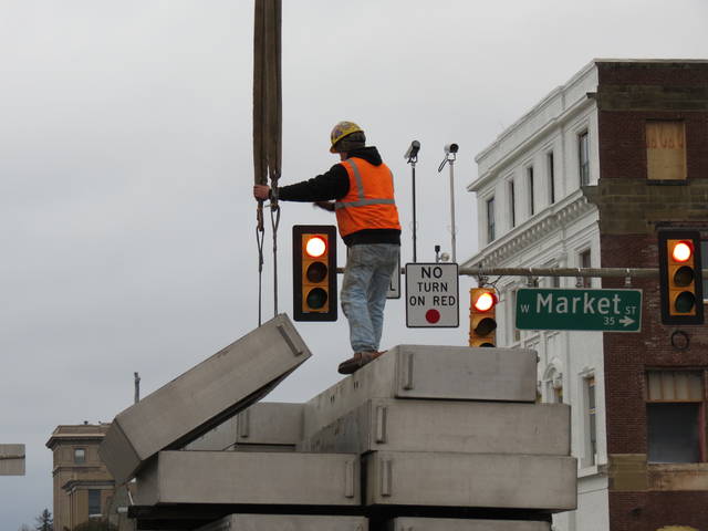 <p>A worker standing atop a truck of floodgate panels on East Market Street gently guides one of the pieces as a crane prepares to lift it into place for insertion between large ribs at the entrance to the Market Street Bridge on Friday afternoon.</p>
<p>Roger DuPuis | Times Leader</p>