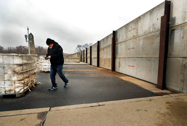 <p>A man checks his phone after taking a photo on the river side of the flood gate on the Market Street Bridge on Friday.</p>
<p>Fred Adams | For Times Leader</p>