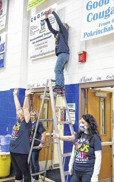 <p>Faculty member Erin Weiss, on top of the ladder, tries to capture the moment when students form the number 2022. Fellow facutly members are Dana Ungureit (hands raised), Theresa Sabetta (behind Ungureit), Tiffany Callaio, right, and Ali Baur (hidden).</p>
<p>Tony Callaio | For Sunday Dispatch</p>