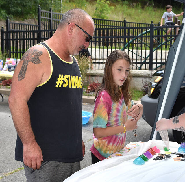 <p>Rhinada Wiedlich, 8, holds a necklace in her hand that she picked out to purchase while her dad Bart looks on.</p>
<p>Tony Callaio | For Sunday Dispatch</p>