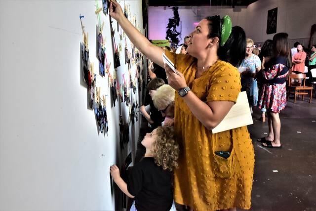 <p>Families eagerly remove photos from the wall at the ANNAMALY Gallery after art camp director Anna Malsky invited them to take home any that they liked.</p>
<p>Mark Guydish | Times Leader</p>