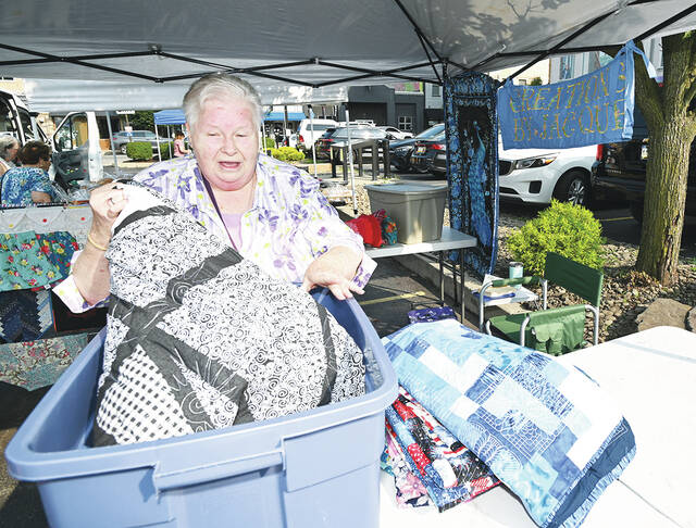 <p>Jacque Troy of Creations by Jacque pulls handmade quilts out of a bin to put on display for the Opening Day of the City of Pittston’s Farmer’s Market on July 11.</p>
<p>Tony Callaio | For Sunday Dispatch</p>