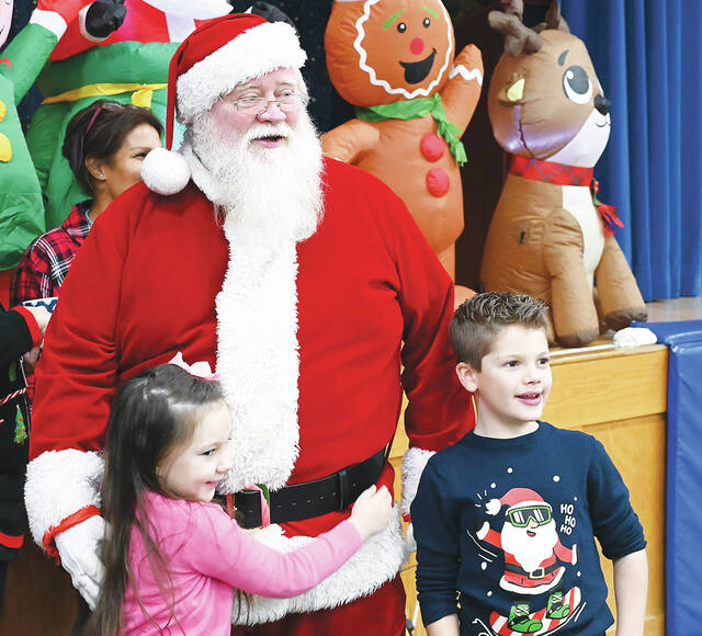 <p>Addie Roberts, left, and Max Drozd, right, give Santa some Christmas hugs during Breakfast with Santa at Wyoming Area Catholic School, Exeter.</p>