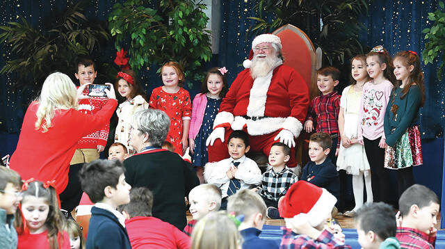 <p>Woming Area Catholic School mom and organizer of Breakfast with Santa, Lisa Pribula, left, is busy taking class photos with Santa.</p>