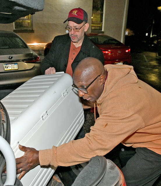 <p>Dwight Houseman, right, and David Kale, back, attempt to get a cooler of turkey dinners in the trunk of a car to deliver.</p>
<p>Tony Callaio | For Sunday Dispatch</p>