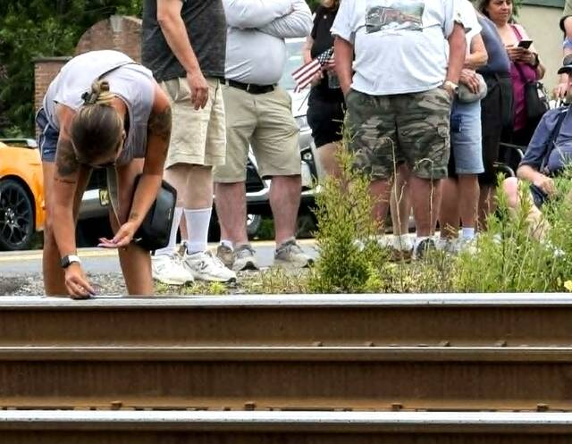 <p>A woman places a penny on the tracks so the copper will be flattened and stretched by the train.</p>
<p>Margaret Roarty | Times Leader</p>