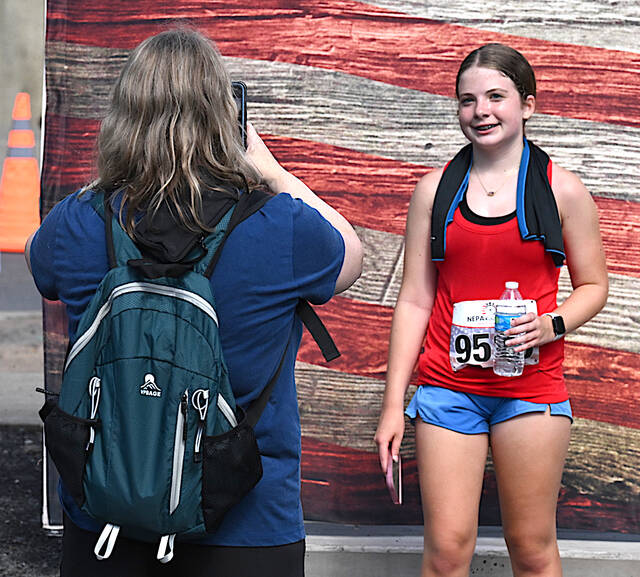 <p>Proud mom Holly Fitch, left, a Pittston native, takes a photo of her daughter, Paige Fitch, 13, of Mountain Top, in front of the American Flag backdrop at the conclusion of the Pittston Patriot Classic 5K race. The Crestwood 8th grader finished first in her age division.</p>
<p>Tony Callaio | For Sunday Dispatch</p>